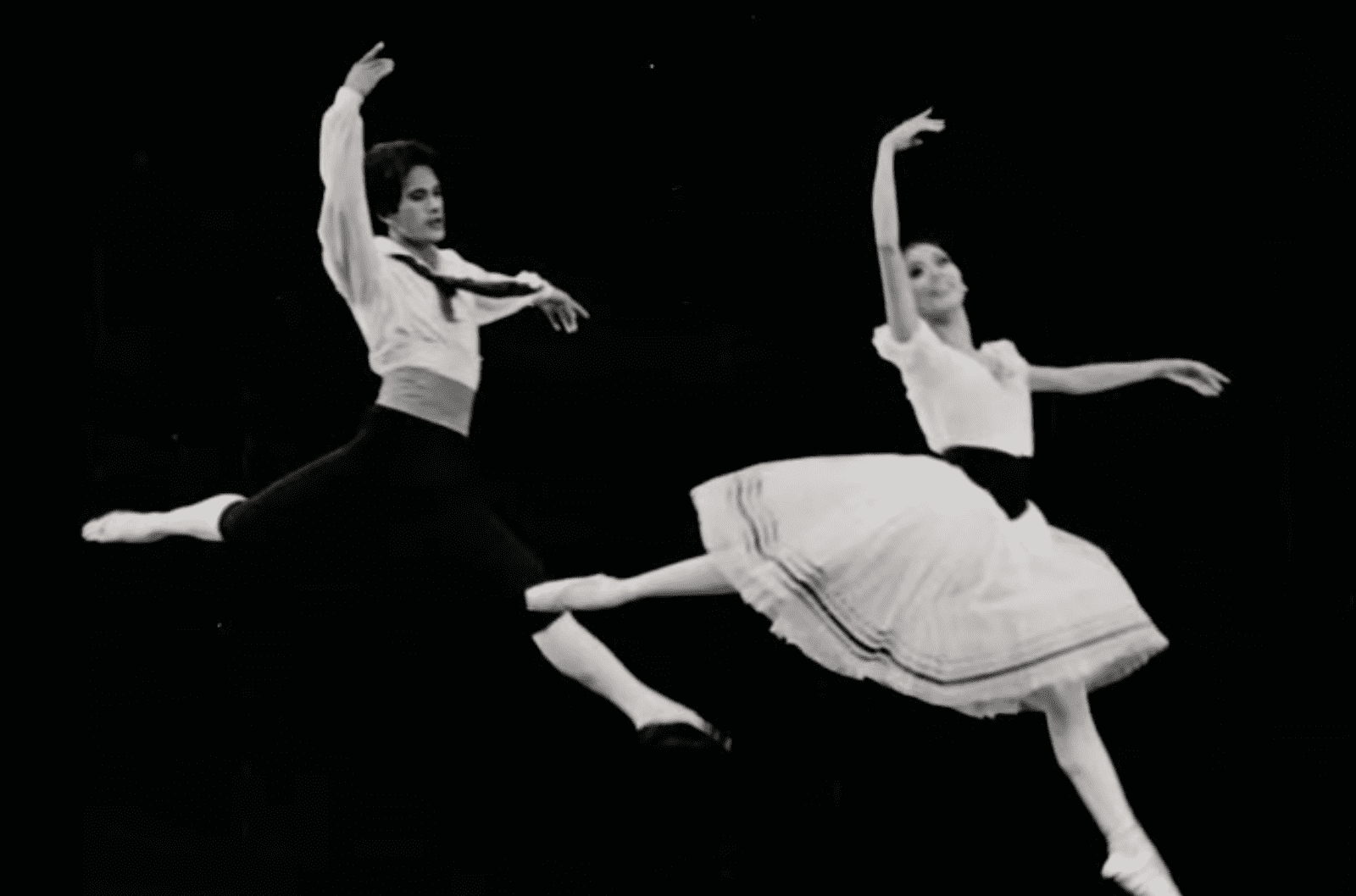 A black and white image of two ballet dancers jumping in mid-air